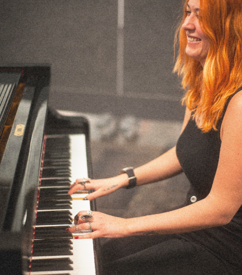 Natalia G. Iglesias sonriendo mientras toca el piano.